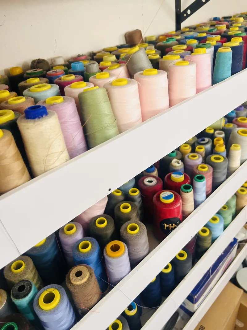 Shelves of thread cones in every colour in the atelier